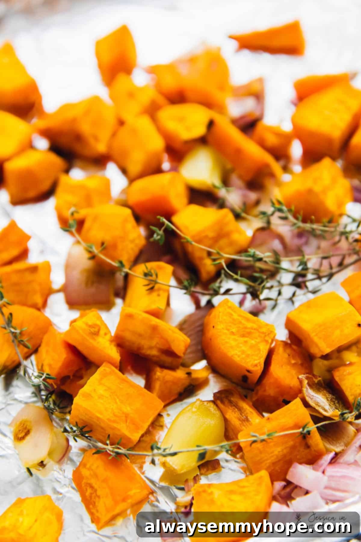 One Pan Roasted Sweet Potato Soup 3 Roasted sweet potato chunks, onions, garlic, and thyme sprigs on a baking sheet.