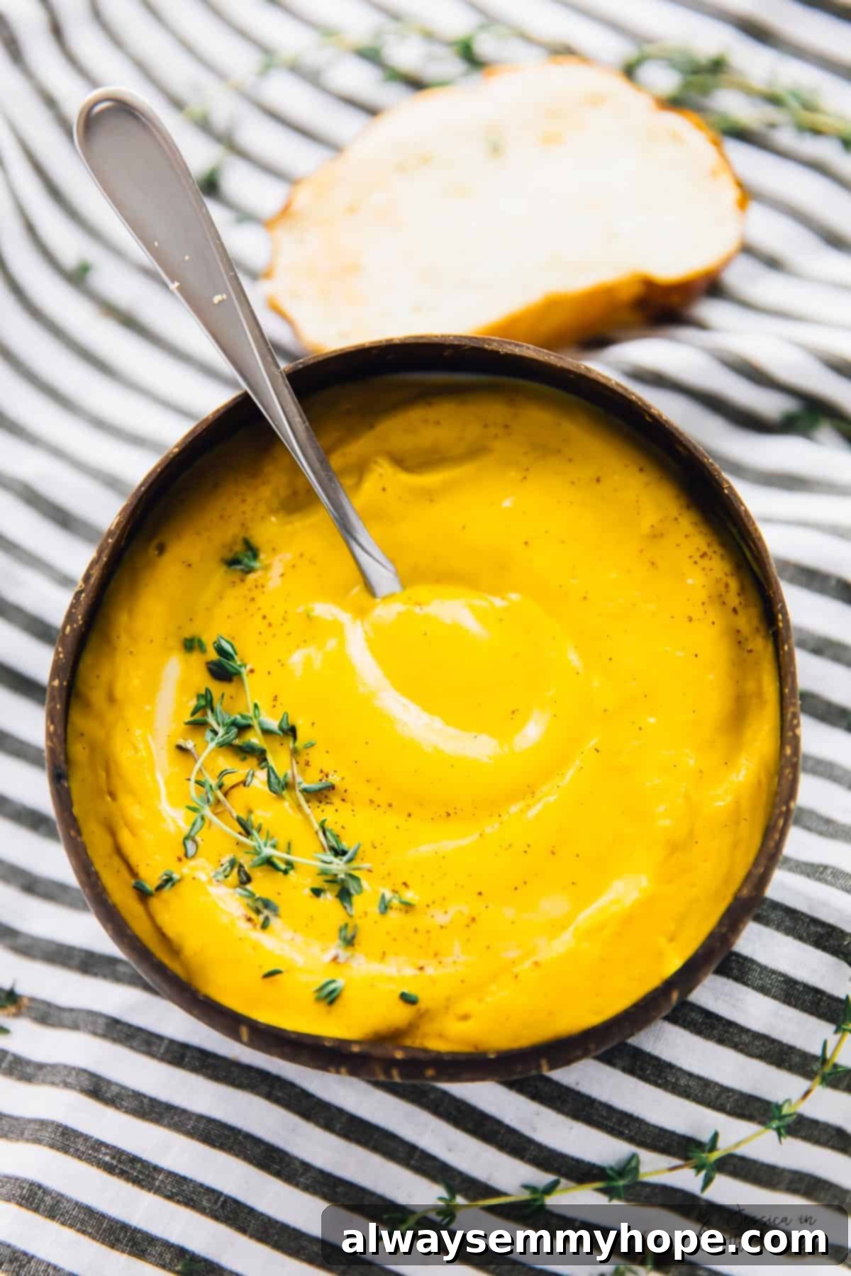 One Pan Roasted Sweet Potato Soup 4 Top-down shot of a fall soup in a bowl, with a spoon in it, garnished with cinnamon and thyme.