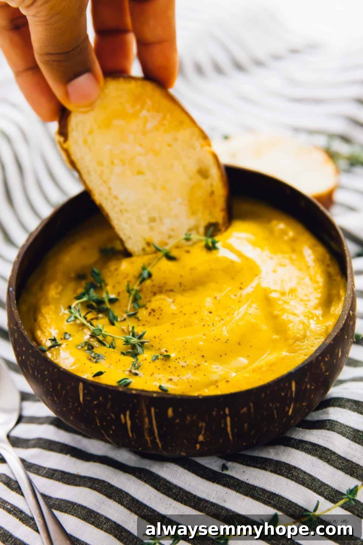 One Pan Roasted Sweet Potato Soup 5 Hand dipping crusty bread into a bowl of roasted sweet potato soup.