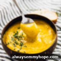 One Pan Roasted Sweet Potato Soup 7 A spoon being dipped into a bowl of roasted sweet potato soup.