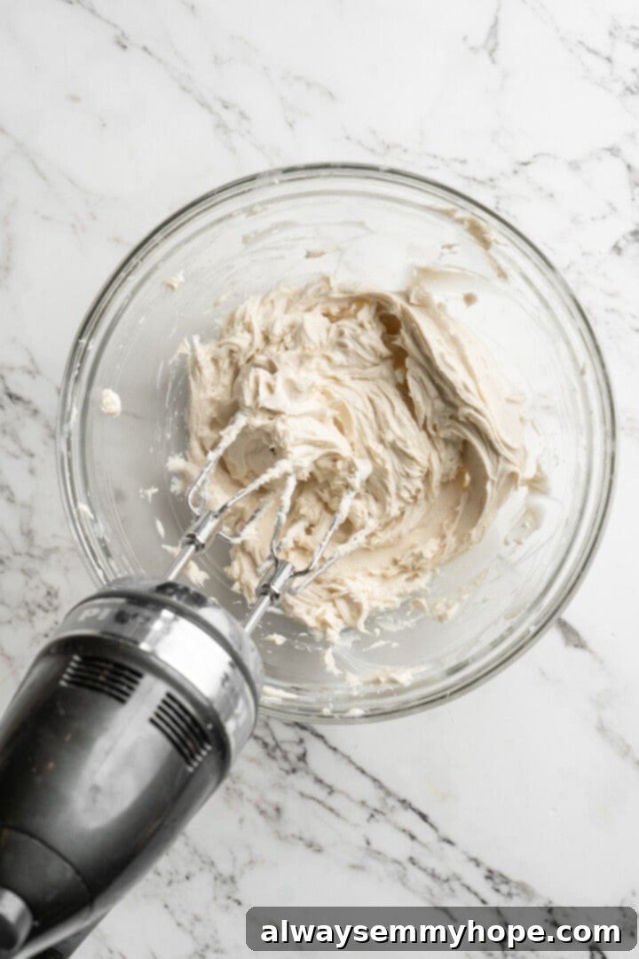These vegan pumpkin cream cheese muffins pair the cozy flavour of pumpkin with a sweet-and-tangy cream cheese filling with delicious results! Overhead view of the smooth and fluffy cream cheese filling mixture in a glass bowl after being blended with a hand mixer.