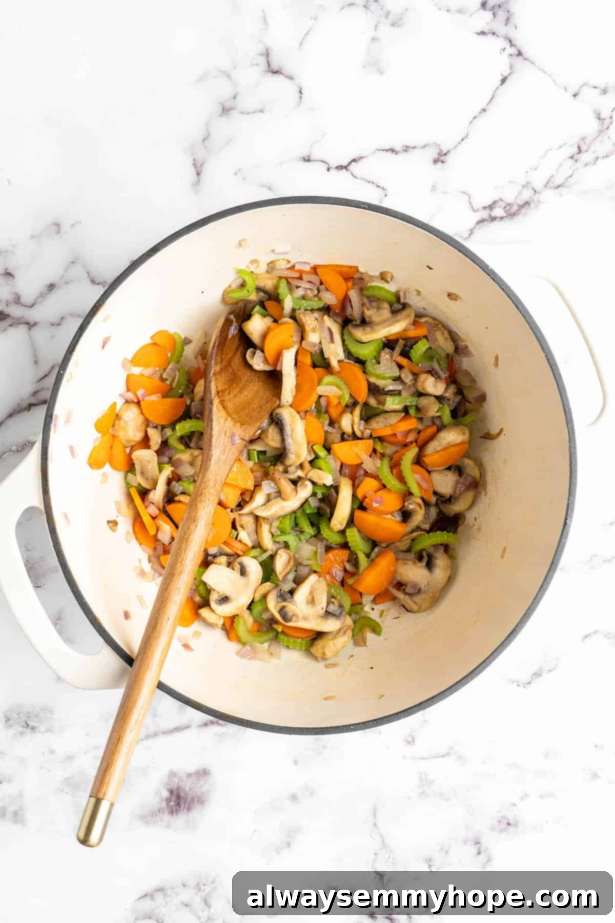 Cooking vegetables in pot with wooden spoon A wooden spoon stirring carrots, celery, red onion, garlic, and sliced mushrooms sautéing in a large pot over medium-high heat. The vegetables are beginning to soften and release their aromas.