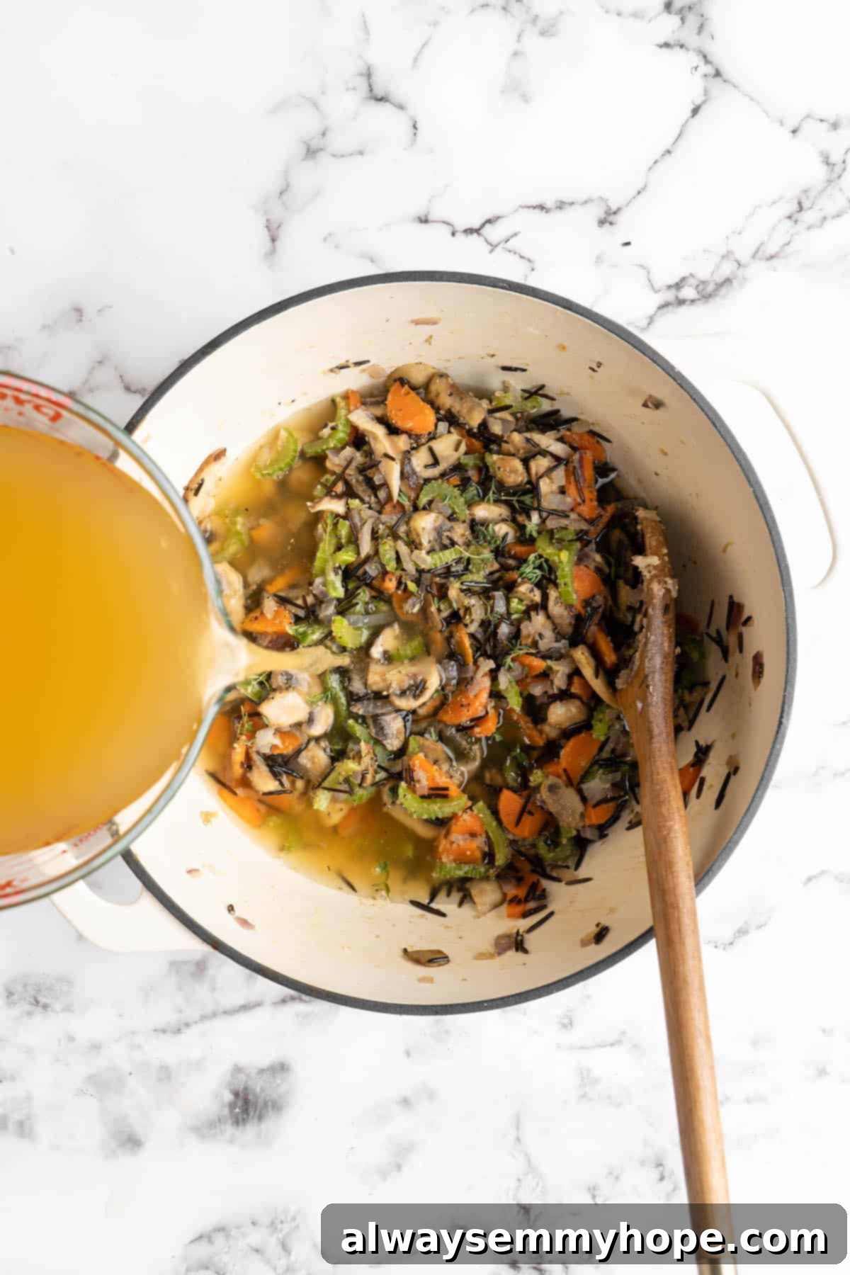 Velvety Vegan Mushroom Wild Rice Soup 5 Vegetable broth being poured into a pot containing sautéed vegetables and mushrooms, ready for the next stage of cooking this creamy vegan mushroom wild rice soup.