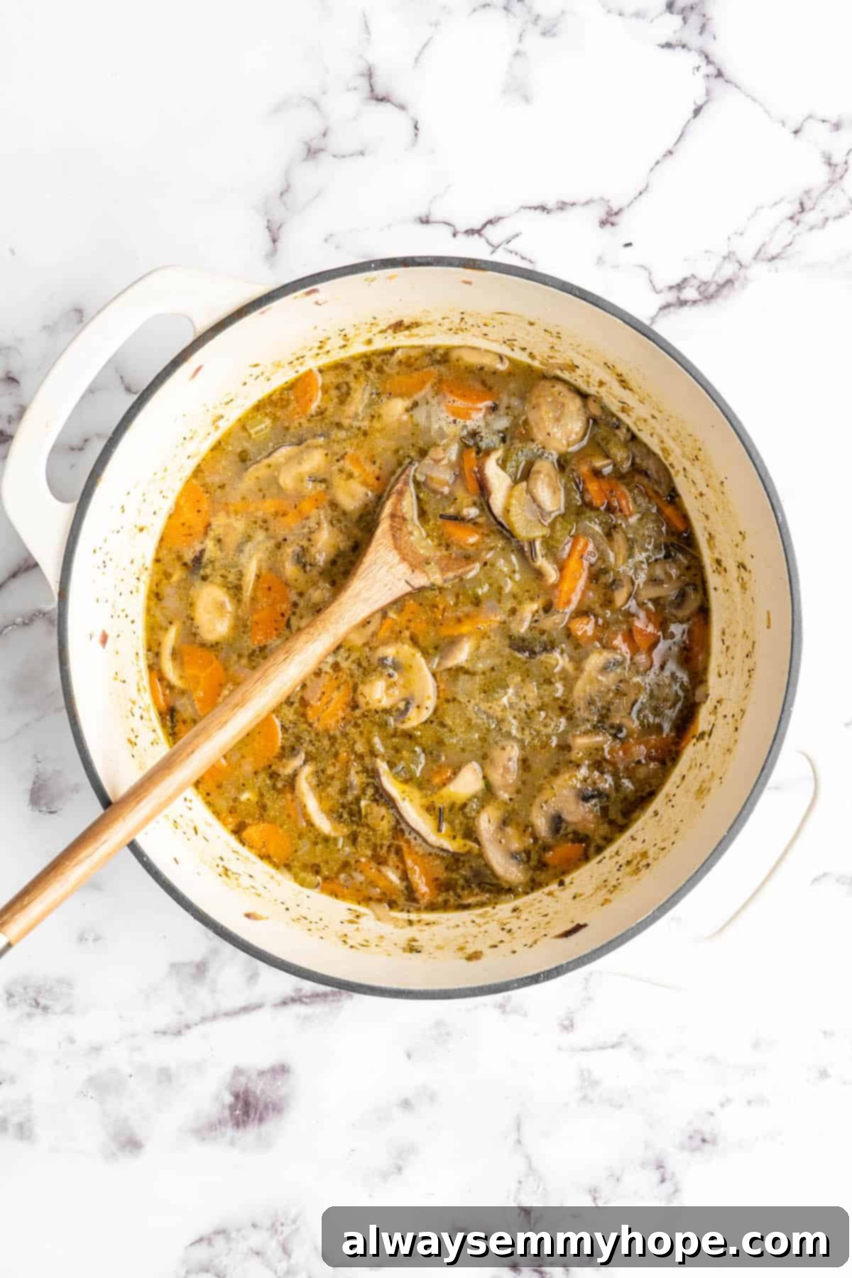 Velvety Vegan Mushroom Wild Rice Soup 6 Overhead view of vegan mushroom wild rice soup simmering in a pot, with the wild rice grains visible and expanding, before the addition of coconut milk.