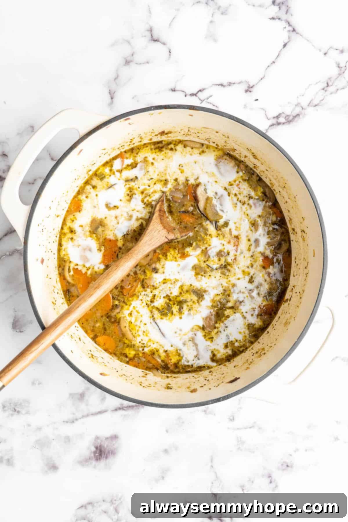 Overhead view of coconut milk being stirred into soup in pot A stream of creamy coconut milk being poured into the simmering vegan mushroom wild rice soup in a pot, with a wooden spoon ready to stir it in.