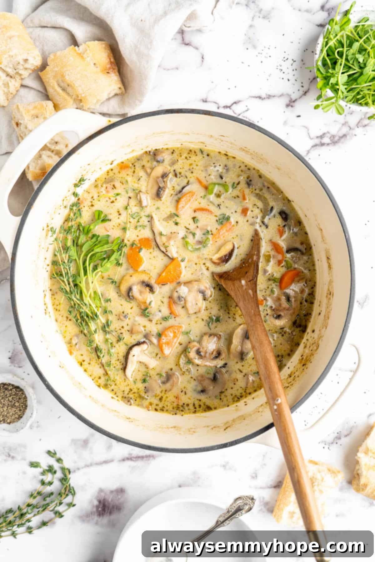 Velvety Vegan Mushroom Wild Rice Soup 8 Overhead view of creamy vegan mushroom wild rice soup in a large pot with a wooden spoon, showcasing its rich texture and hearty ingredients.
