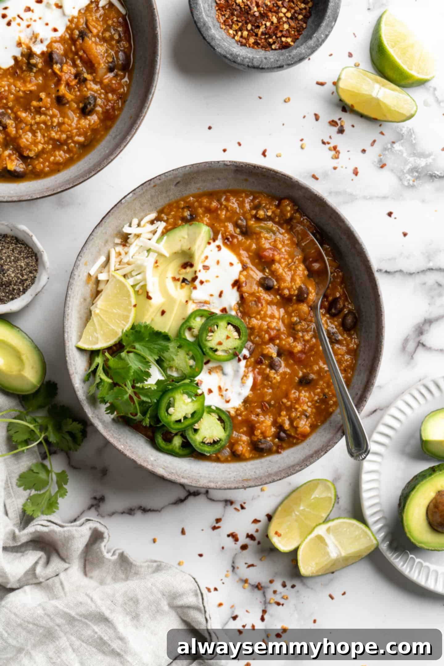 A beautifully presented bowl of vegan pumpkin chili, garnished with fresh jalapeños and creamy avocado slices, ready to be enjoyed.