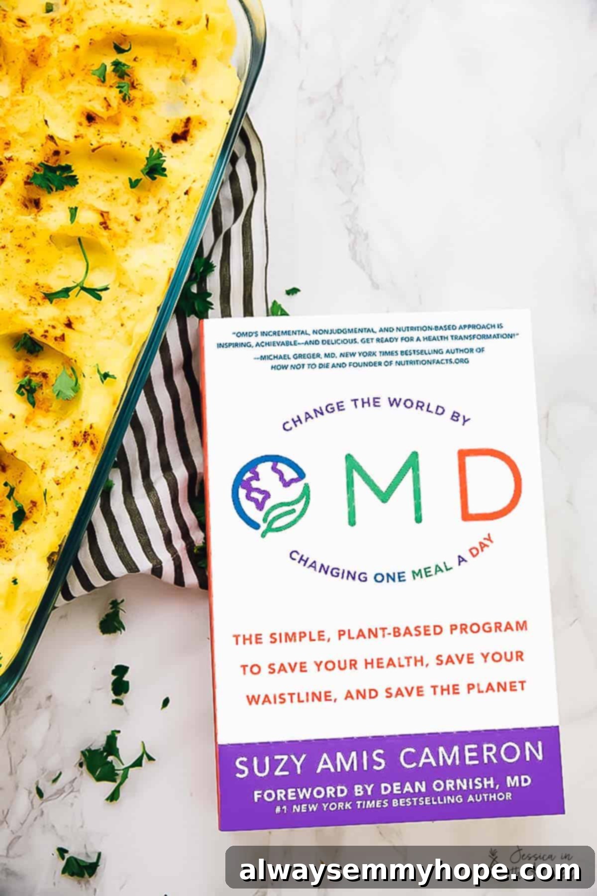 Regal Shepherd's Pie 3 An inviting overhead view of a freshly baked vegan shepherd's pie, artfully placed next to the OMD cookbook on a rustic surface.