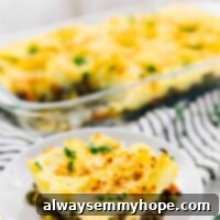 Regal Shepherd's Pie 7 A portion of vegan shepherd's pie on a white plate with more pie in the background, in a baking dish.