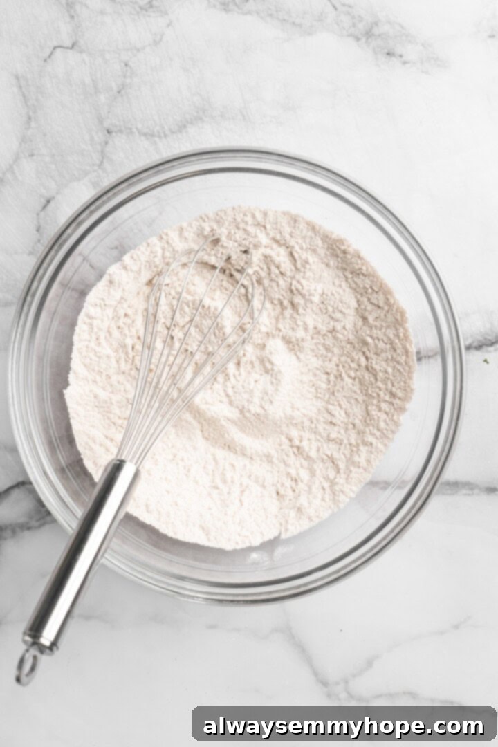 Decadent Chewy Salted Tahini Chocolate Chip Cookies 2 Dry ingredients like flour, baking powder, baking soda, cinnamon, and salt being mixed in a bowl.