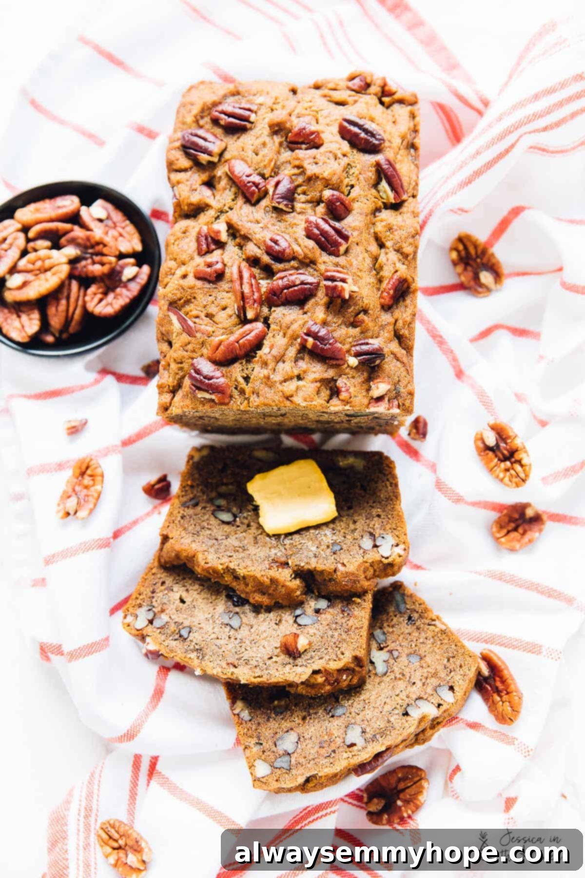 Delicious Vegan Gluten Free Pecan Banana Bread 2 A perfectly sliced loaf of gluten-free pecan banana bread on a rustic cloth, surrounded by whole pecans and banana slices.
