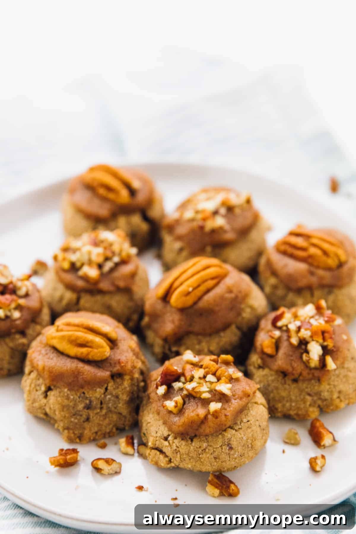 Golden Maple Pecan Sugar Cookies 2 Close-up shot of perfectly baked maple pecan sugar cookies arranged on a white plate, showcasing their inviting texture and festive appeal with a sprinkle of chopped pecans.