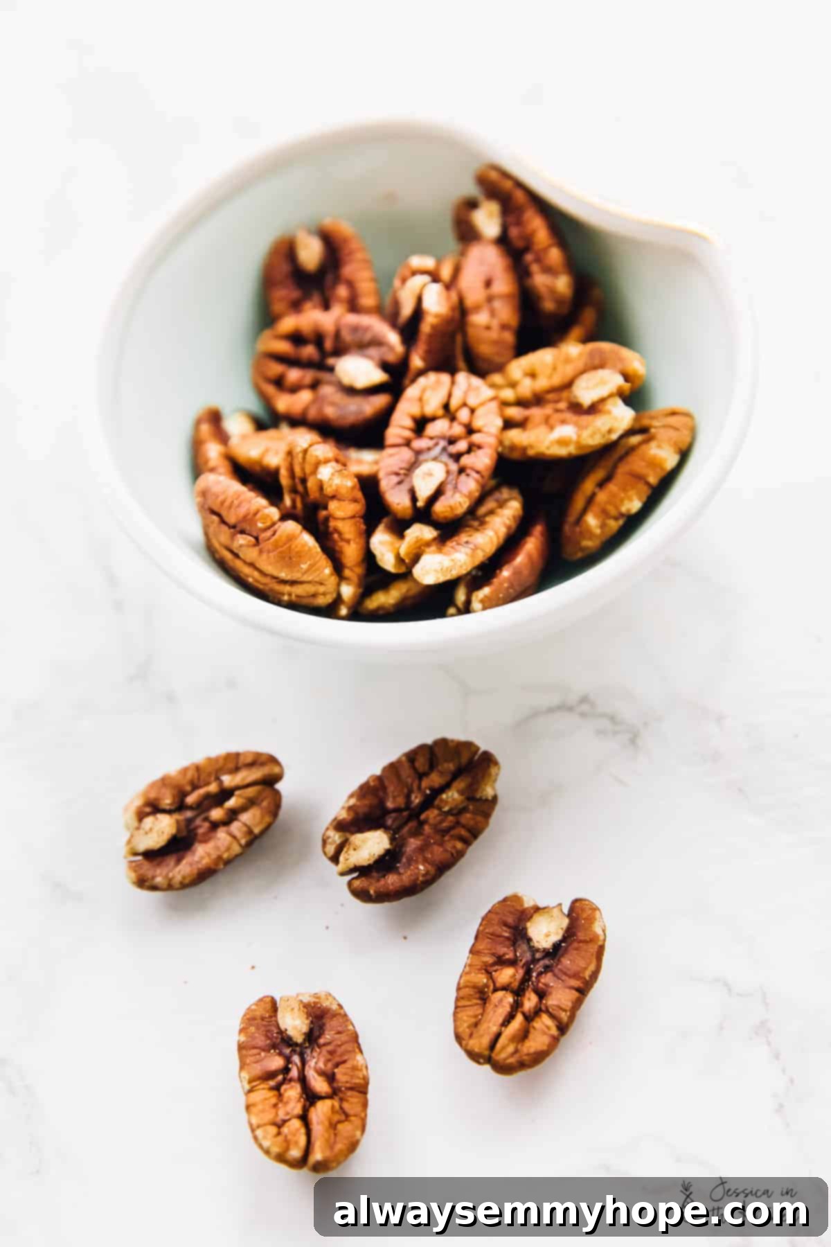 Golden Maple Pecan Sugar Cookies 3 A rustic wooden bowl filled with whole, fresh pecan halves, surrounded by loose pecans scattered on a light, textured surface, ready for baking.