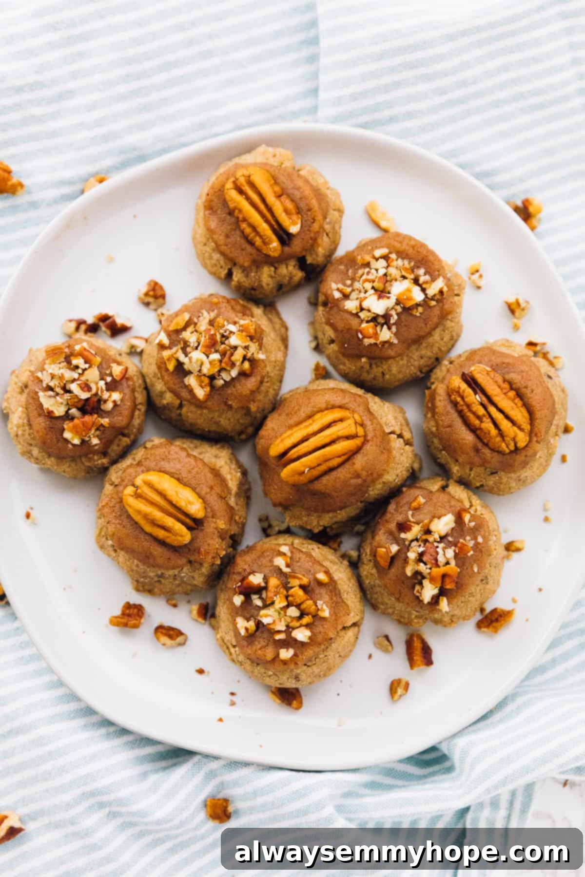 Golden Maple Pecan Sugar Cookies 5 A stunning arrangement of elegantly frosted maple pecan sugar cookies, topped with glistening pecan pieces, laid out on a clean white plate, creating a tempting holiday visual.