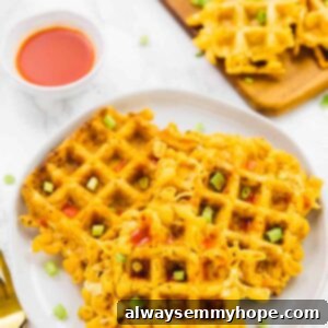 Mac and cheese waffles on a white plate, with sauce on the side.