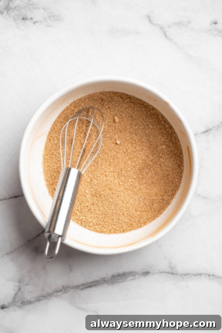 Overhead view of cinnamon sugar being mixed in a bowl with a whisk.