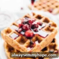 Syrup being poured onto delicious vegan and gluten-free orange cranberry waffles, perfect for a holiday breakfast.