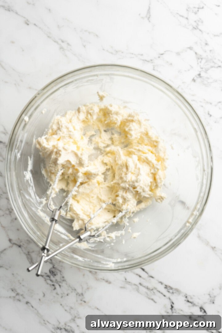 Moist, rich red velvet brownies are perfect for a special occasion or anytime you’re craving a decadent dessert. With cream cheese frosting! Overhead view of softened vegan butter and vegan cream cheese being creamed together in a mixing bowl with electric beaters, creating a smooth, pale mixture.