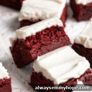 Crimson Velveteen Brownies 2 Red velvet brownies on parchment paper, with one tipped sideways to show moist crumb