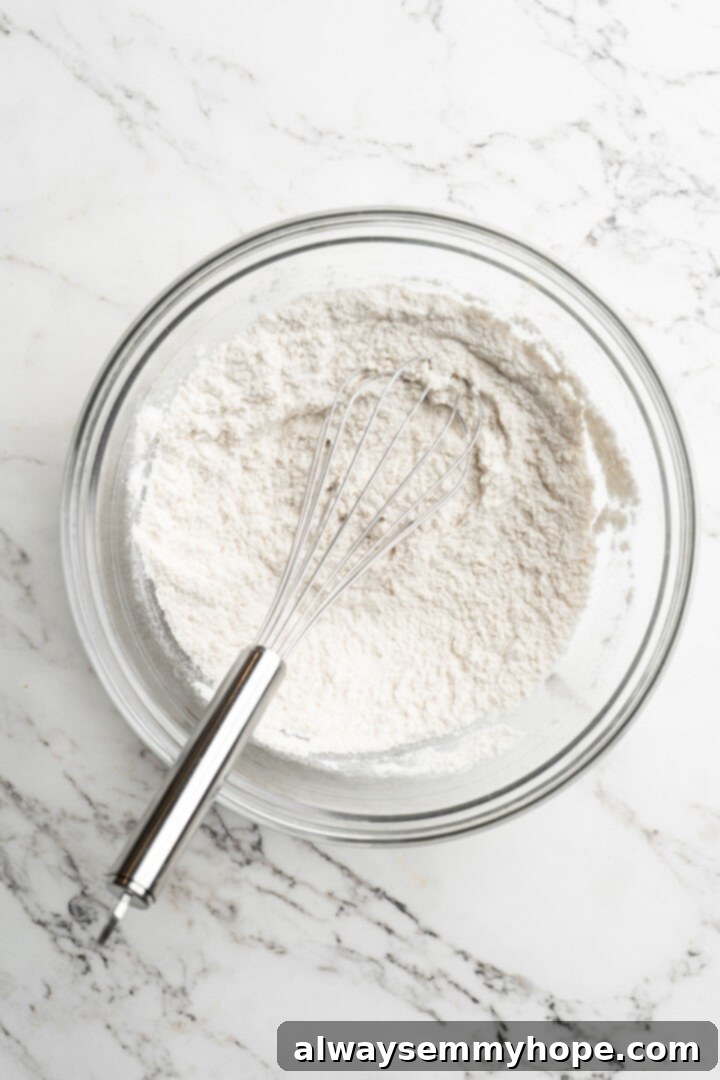 Moist, rich red velvet brownies are perfect for a special occasion or anytime you’re craving a decadent dessert. With cream cheese frosting! Overhead shot of all-purpose flour and sea salt perfectly combined in a white ceramic mixing bowl, ready for whisking.