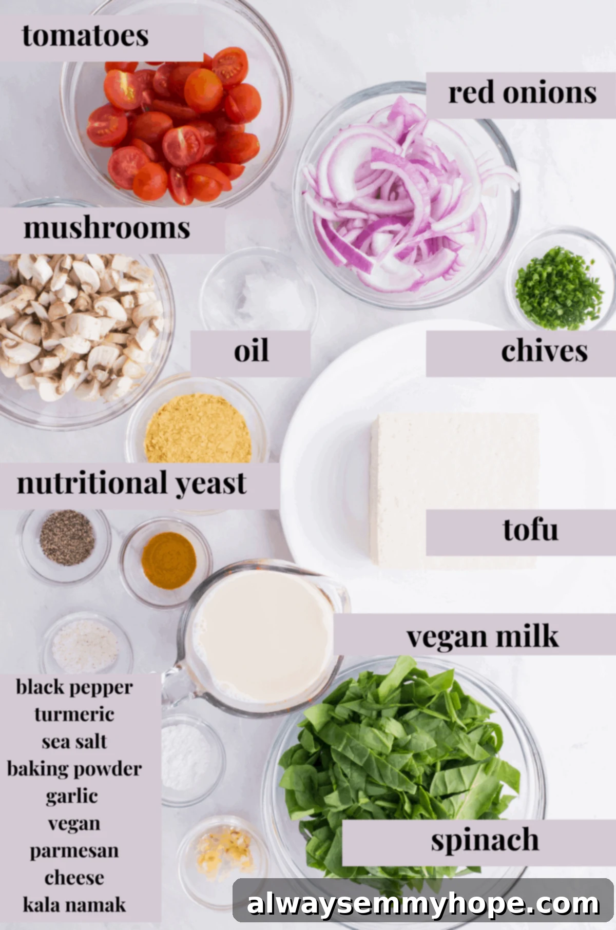 A vibrant display of fresh ingredients for vegan quiche, including firm tofu, cherry tomatoes, red onion, mushrooms, spinach, garlic, and various seasonings, ready for preparation.
