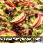 Shaved Brussels sprout salad with apples, walnuts, and cranberries in serving bowl.