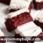 Red velvet brownies on parchment paper, with one tipped sideways to show moist crumb