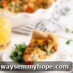 Slice of quiche on plate with greens, with glass of orange juice in background