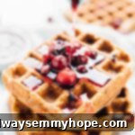 Syrup being poured onto orange cranberry waffles.