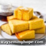 cornbread muffins in a stack with maple syrup drizzled on top and a pat of butter