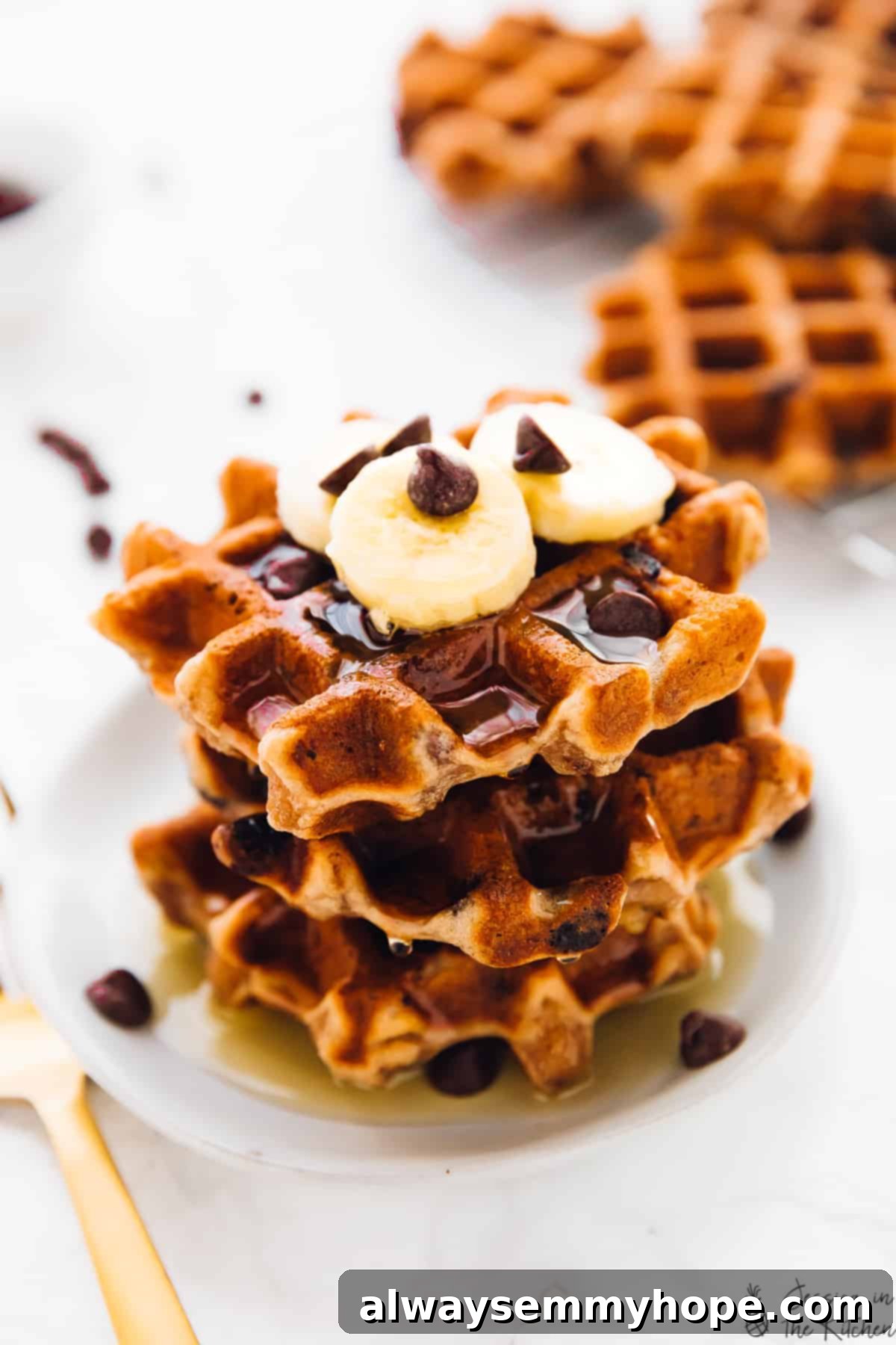 A close-up shot of three golden banana bread waffles, perfectly stacked and lightly drizzled with syrup, highlighting their inviting texture and rich color.