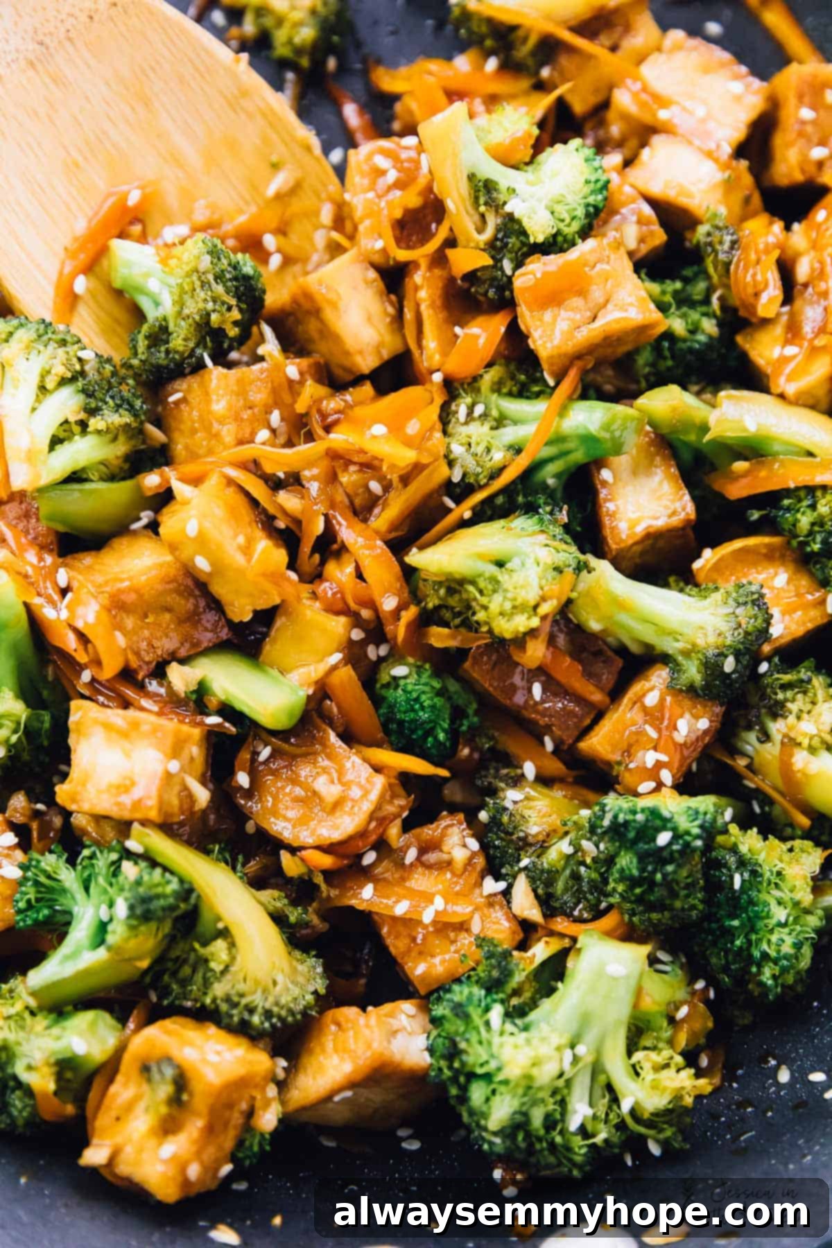 10 Quick & Easy Vegan Fakeaway Recipes 7 A wooden spoon stirring tofu and veggie stir fry in a skillet.