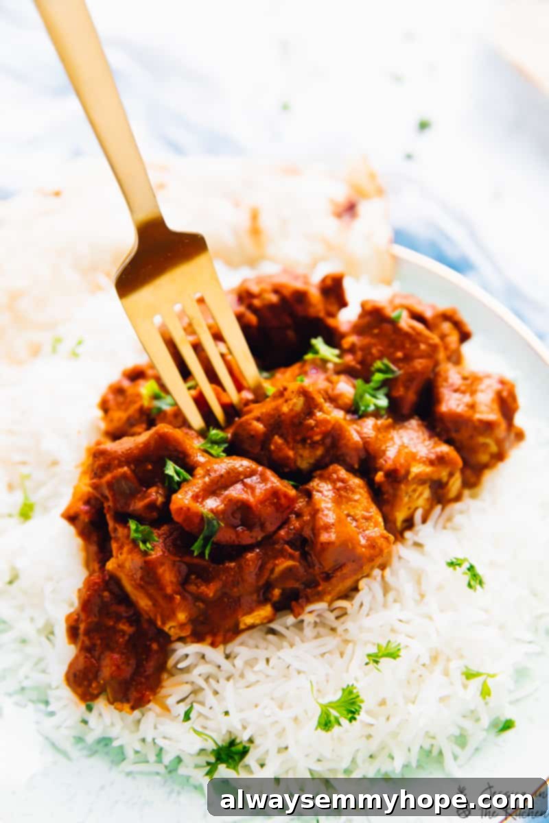 Slow Cooker Vegan Tofu Butter Chicken 5 A fork taking a bite of tender tofu butter chicken, showing the rich, creamy texture and succulent tofu.