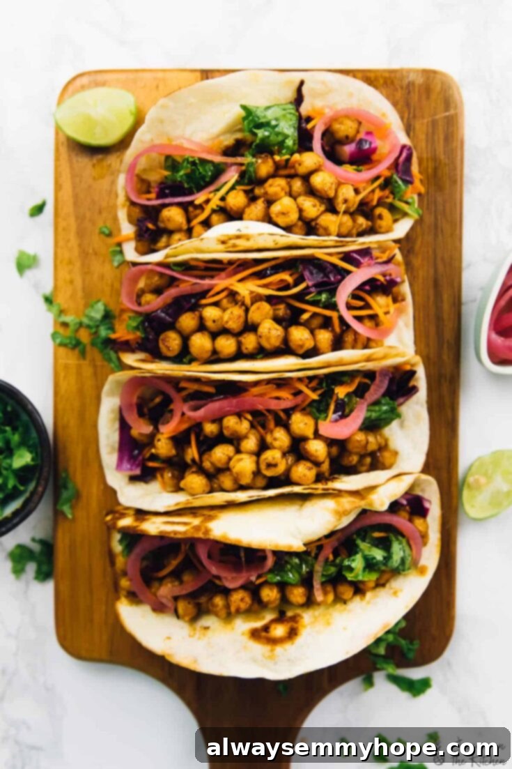 Two colorful BBQ chickpea tacos, generously topped with fresh kale cabbage slaw and tangy pickled onions, ready to be enjoyed.