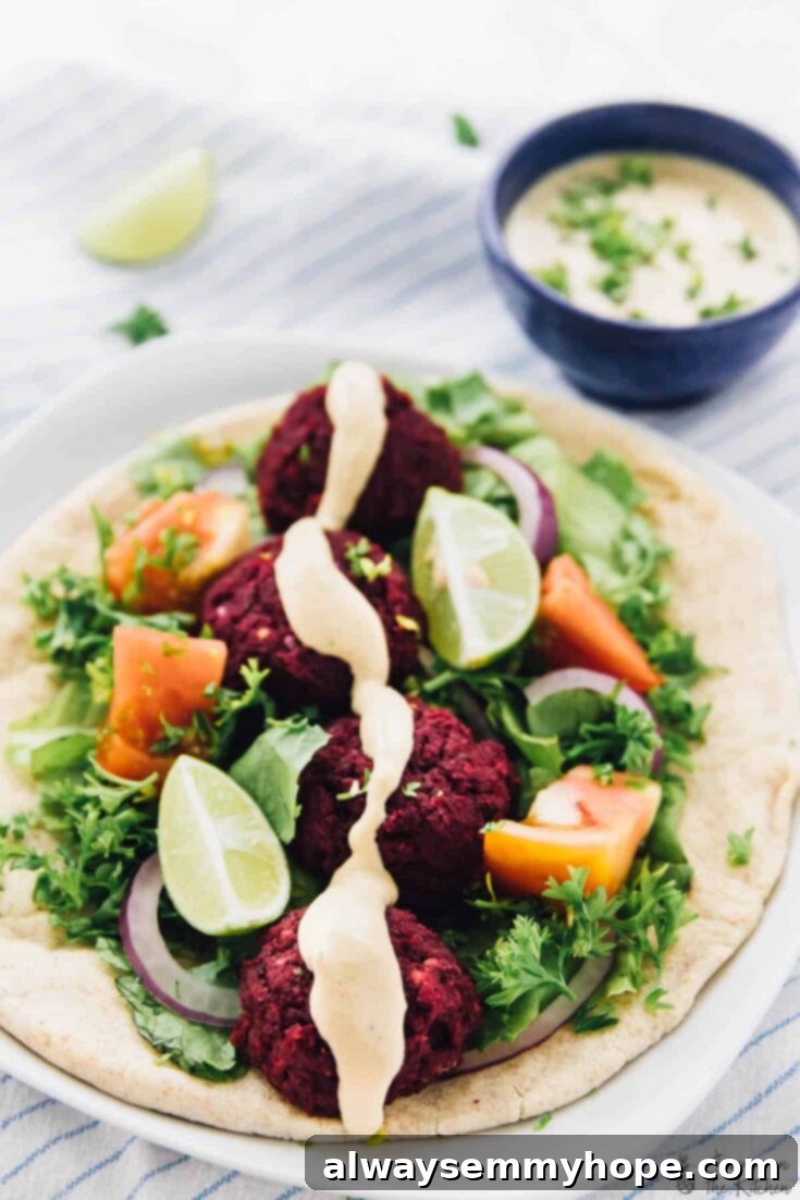 Vibrant vegan beet falafel patties, baked golden, served beautifully with a creamy harissa tahini dressing and fresh herbs.