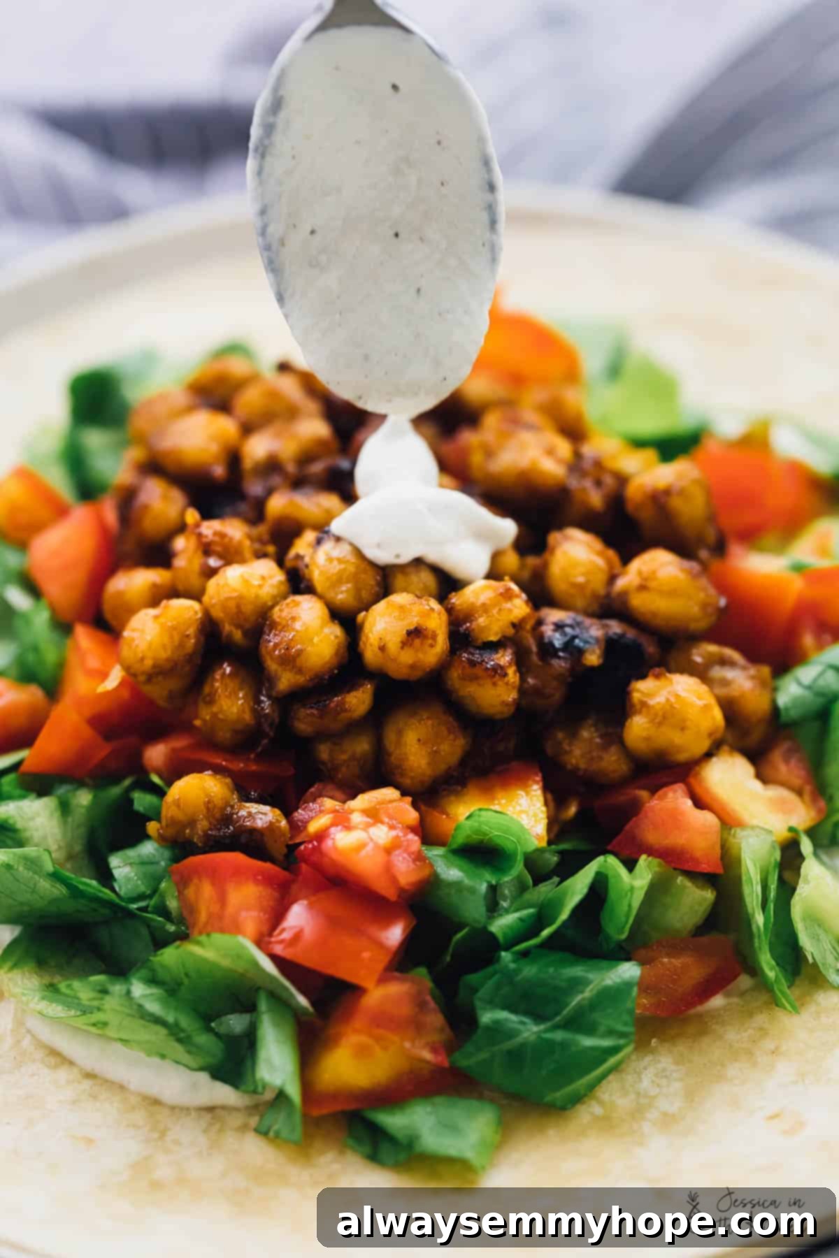 A beautifully plated BBQ Chickpea Wrap with creamy ranch dressing, garnished with fresh herbs, showcasing a delicious and portable meal option.