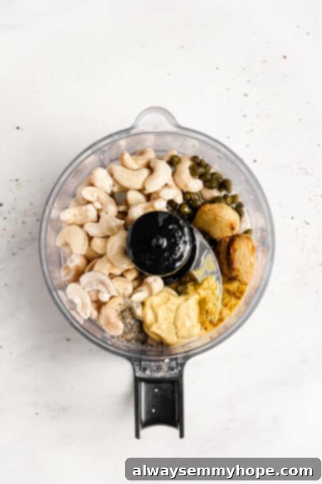 Vegan Caesar salad is perfect as a quick side dish or a light dinner! It’s made with a tangy dressing, crunchy croutons, and crisp lettuce. Various ingredients for vegan Caesar dressing, including tahini, capers, and garlic, placed in a blender carafe before mixing.