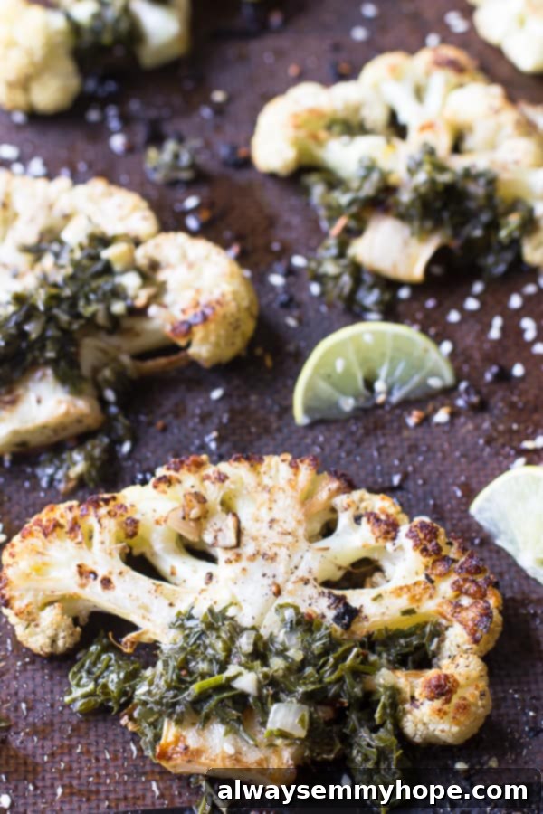 Cauliflower steaks on a baking sheet, with a lemon wedge.