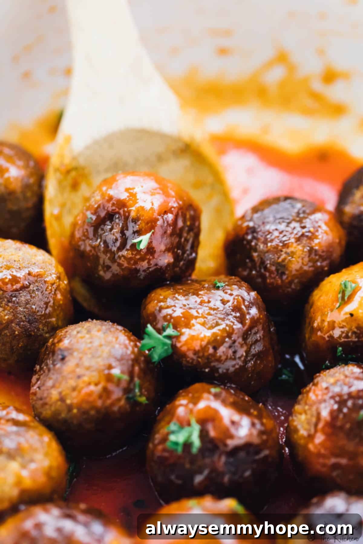 Vegan meatballs being stirred in a pot with a wood spoon.