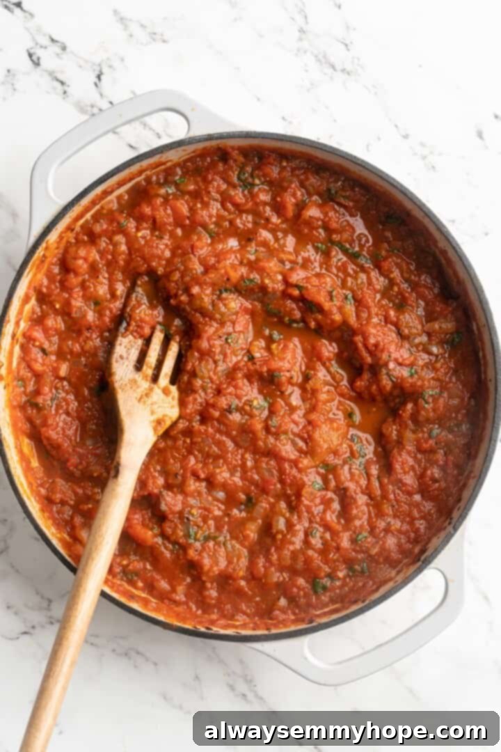 Overhead view of finished spicy arrabbiata sauce in a skillet, garnished with fresh basil, ready to be served.