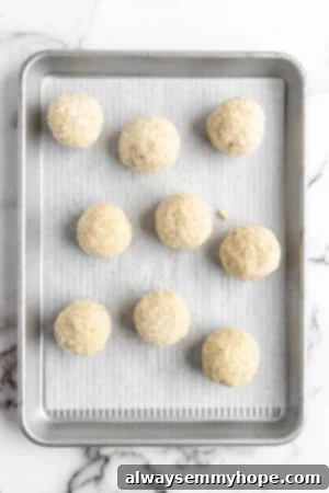 These vegan arancini are crispy, stuffed with melty mozzarella, and perfect for appetisers! Fry them the traditional way or use an air fryer! Overhead view of uncooked arancini on parchment-lined pan
