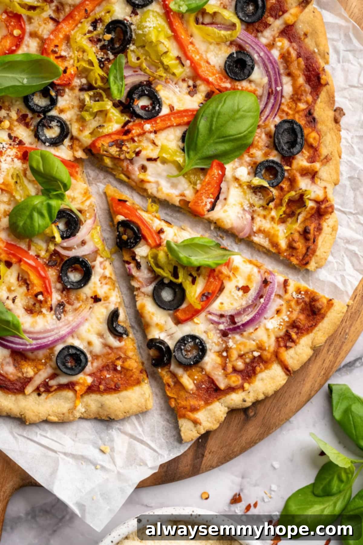 Top-down view of almond flour pizza slice pulled away from rest of pizza, highlighting the crispy crust and delicious toppings.