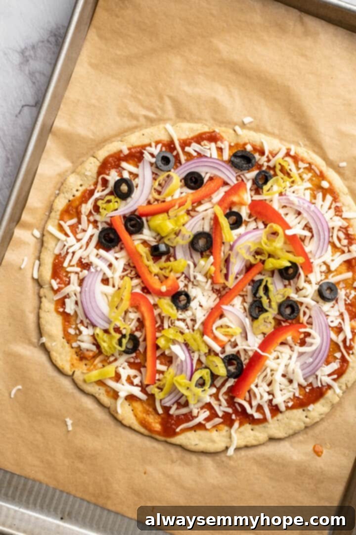 Overhead view of a vegetable pizza with almond flour crust, topped and ready for its final bake.