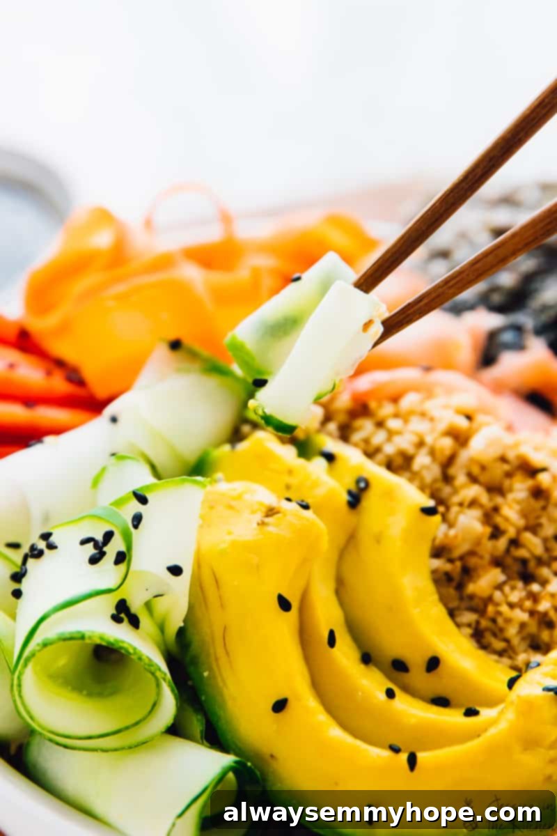 Chopsticks picking up some cucumber from a sushi bowl. 
