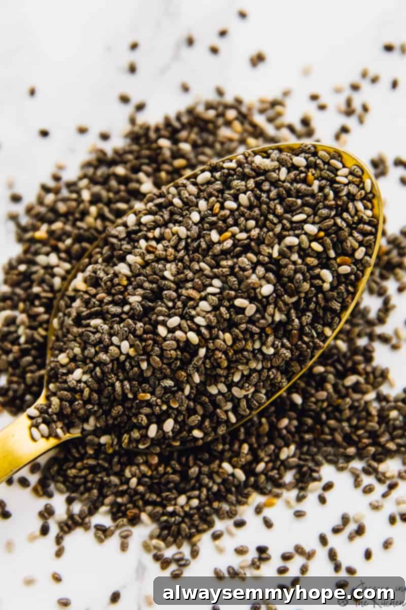 A close-up shot of small, black chia seeds scattered over a wooden spoon, highlighting their tiny size and texture.
