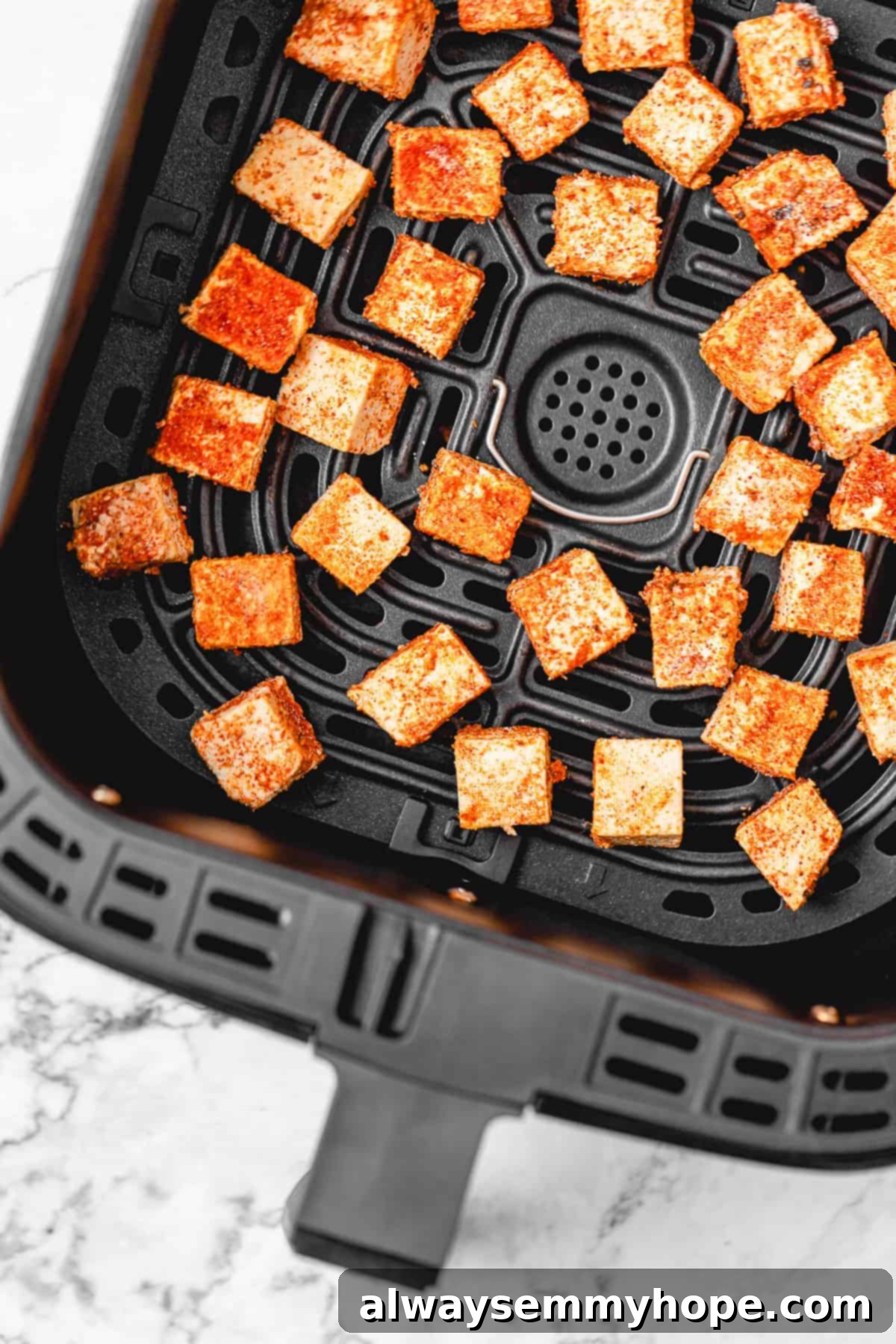 seasoned tofu cubes unbaked in an air fryer tray