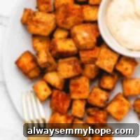 air fryer tofu on a plate with sauce and a gold fork