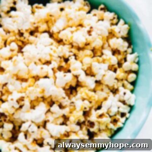 A bowl of cheesy popcorn in a blue bowl, garnished with fresh herbs.