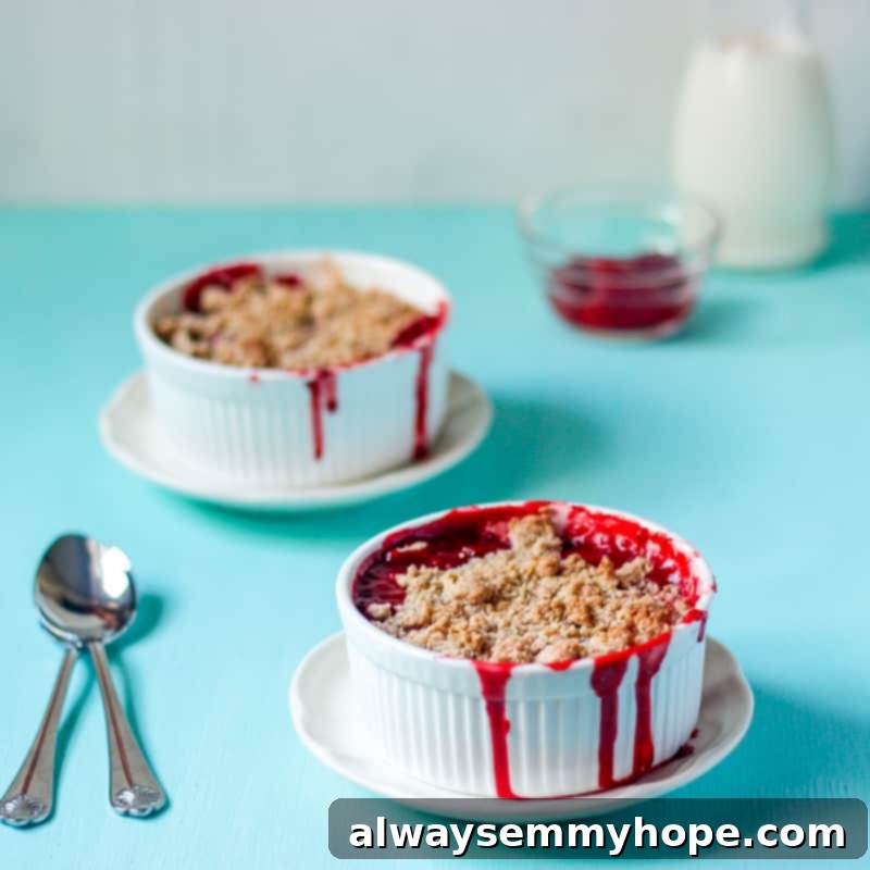 Two ramekins filled with warm 5-Ingredient Strawberry Crumble, presented on a rustic blue table.
