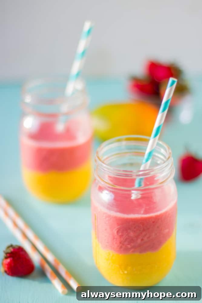 Two vibrant strawberry mango smoothies in mason jars with straws, perfect for a refreshing treat.
